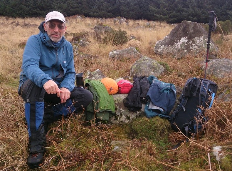 a man sitting on a rock in the middle of a field