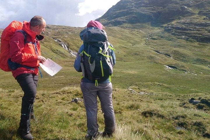 a group of people standing in a field with a mountain in the background