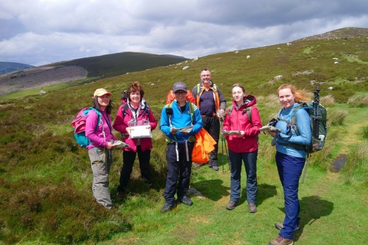 a group of people standing on a grassy hill