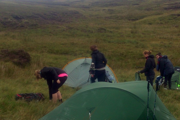 a person in a green tent on a grassy hill